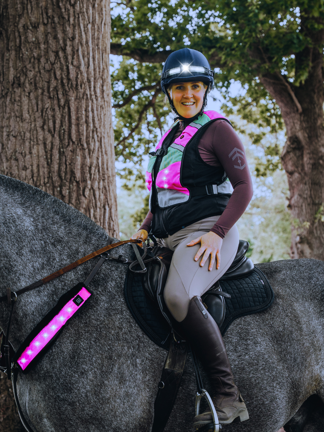 woman riding a horse wearing an EquiLight  led hi-vis vest, led headtorch and led hi-vis martingale sleeve