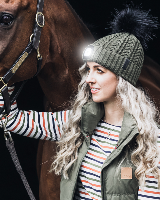 EquiLight Merino LED Pom Beanie with rechargeable hands-free LED light for outdoor visibility, Merino wool pom beanie with integrated rechargeable LED light by EquiLight, Person wearing EquiLight merino LED pom beanie for hands-free lighting outdoors, Close-up of integrated LED light on EquiLight merino pom beanie, Soft merino wool pom beanie with built-in LED light designed for warmth and comfort